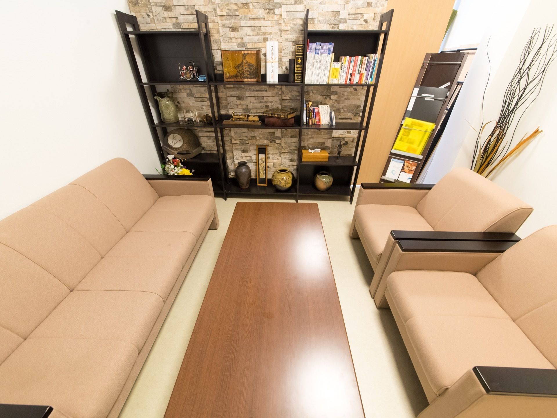 ブラウン系で統一された、落ち着いた雰囲気の休憩スペース。ソファセットやマガジンラックが置かれている。