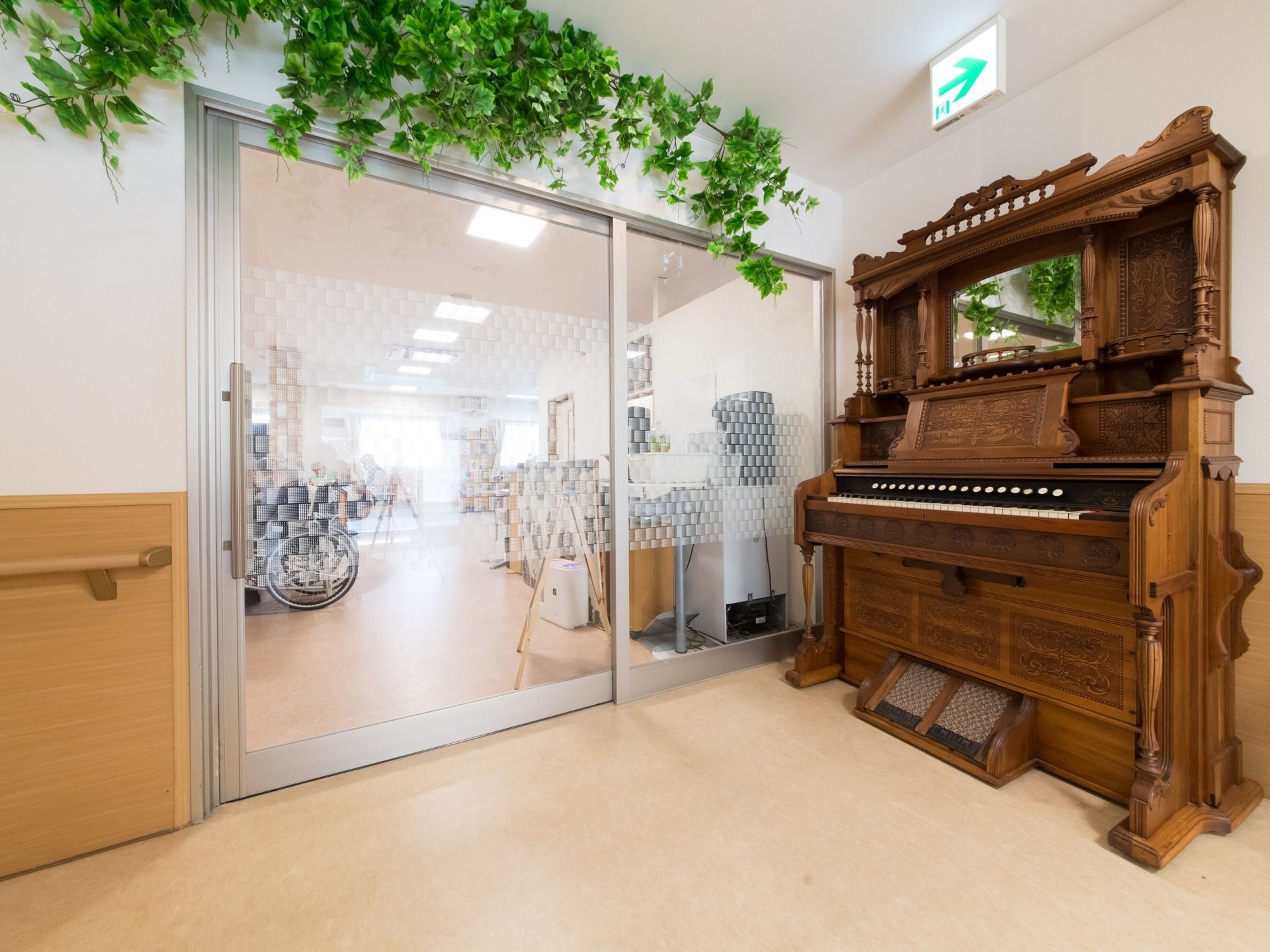 入り口の扉は大きく開く引き戸タイプになっている。入り口付近に置かれている重厚な雰囲気のオルガン。壁はグリーンの造花で飾られている。