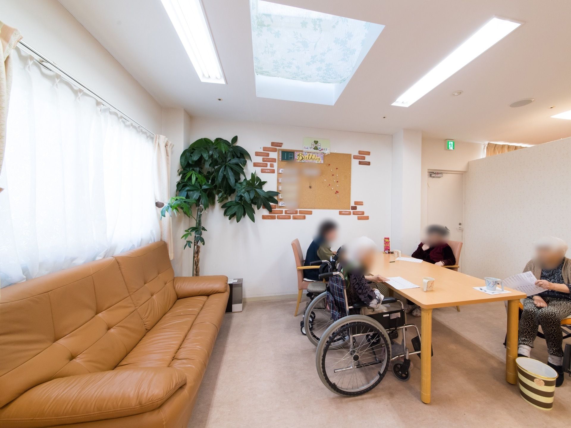 休憩スペースには、テーブルと椅子の他、ゆったりとした革張りのソファが置かれている。入居者様が集い、お茶を飲んでいる。