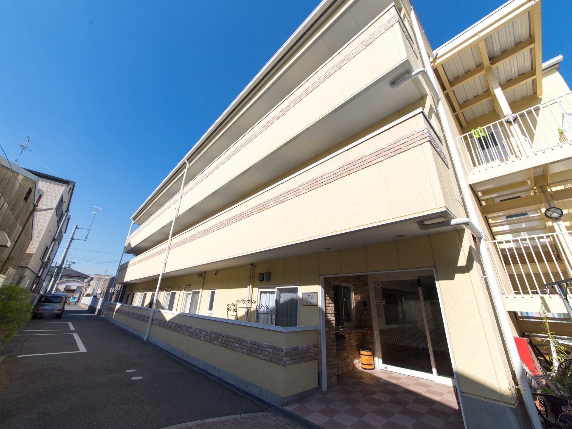 閑静な住宅街に立地している施設の外観。外壁はベージュを基調とした明るい雰囲気になっている。敷地内に駐車スペースがある。