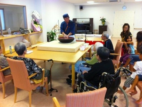 職人が料理をふるまう様子を、取り囲んで見つめる入居者たち