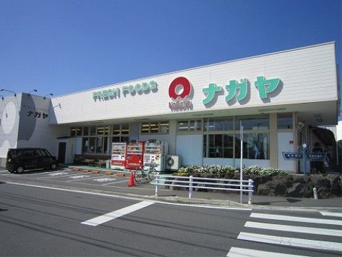 白の外壁に、淡い緑で文字が書かれたスーパーがある。店の前には自動販売機が三つ置かれており、駐車スペースもある。