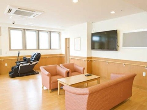 ソファとテーブル、マッサージチェア、壁掛けテレビが置かれた部屋
