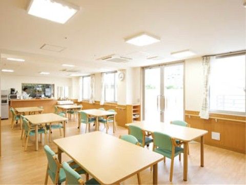大きな窓がたくさんあり、日当たり、風通りの良いダイニングルームである。車椅子にも対応したテーブルが設置されている。