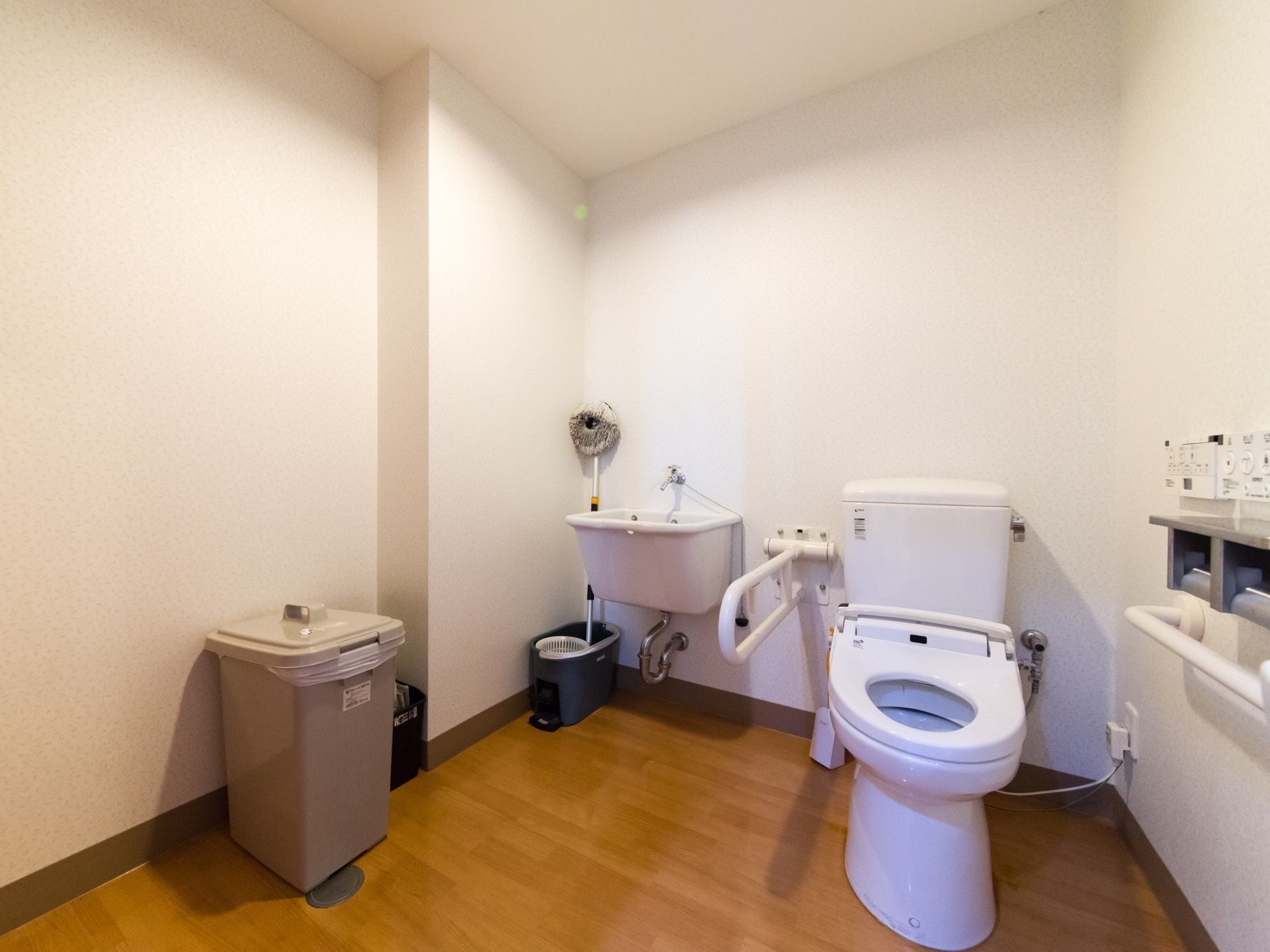 白いトイレがあるスペースには、モップを洗うのに適したユーティリティシンクが設置されている。トイレットペーパーが２つ掛けられるホルダーがある。