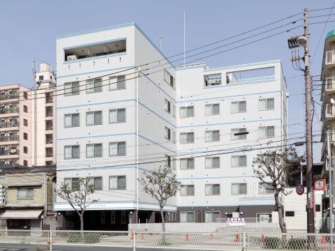 街路樹のある大通りに面しており、窓が等間隔に並んでいる建物