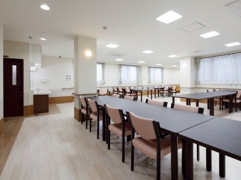 複数のテーブルと椅子が並べられた、窓が多く広い食堂