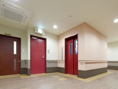 壁に手すりがついた通路と、赤い扉のついたエレベーター