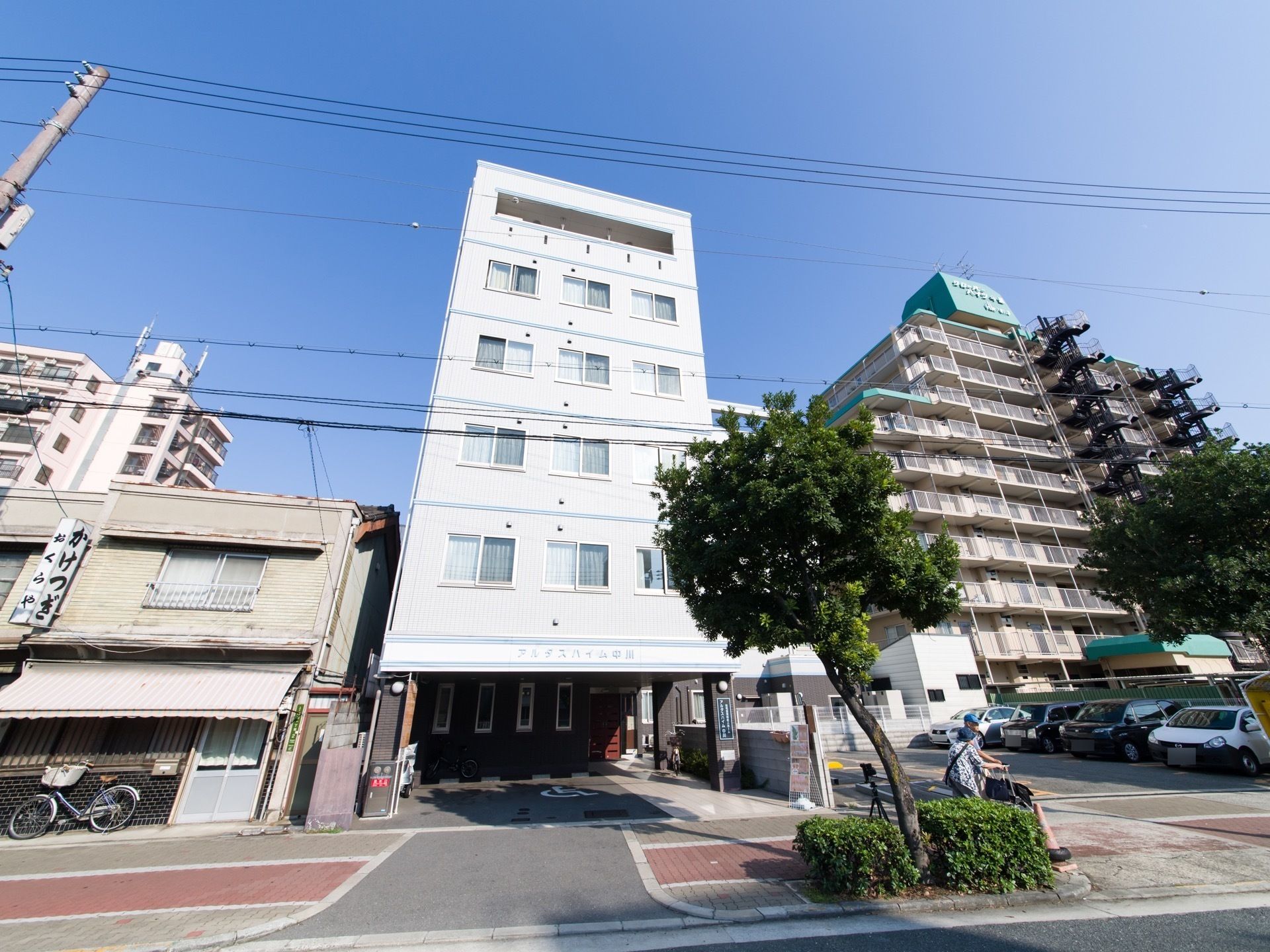 道路に面して立地している施設の敷地内には広いスペースの駐車場がある。道路からのアプローチは段差のないバリアフリー仕様になっている。