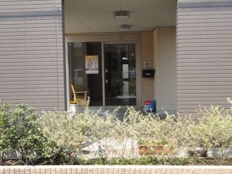 周囲に植栽が施され、自動ドアが設置された庇付きの玄関