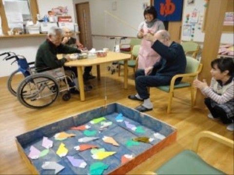 おもちゃの釣り竿で、紙の魚を釣り上げようとする入居者