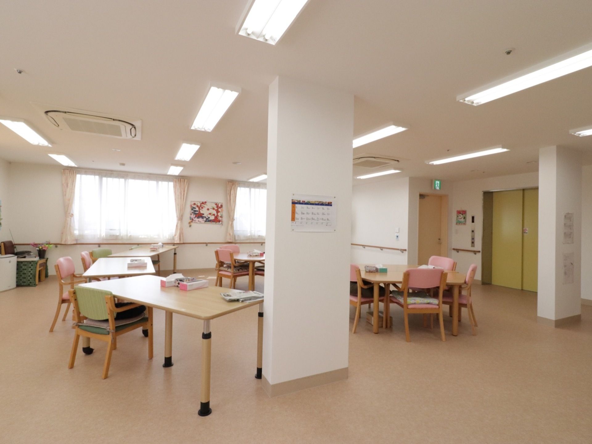 室内に構造柱が２本立てられ、カレンダーが掛かっている。天井には業務用エアコンと蛍光灯の照明が設置されている。
