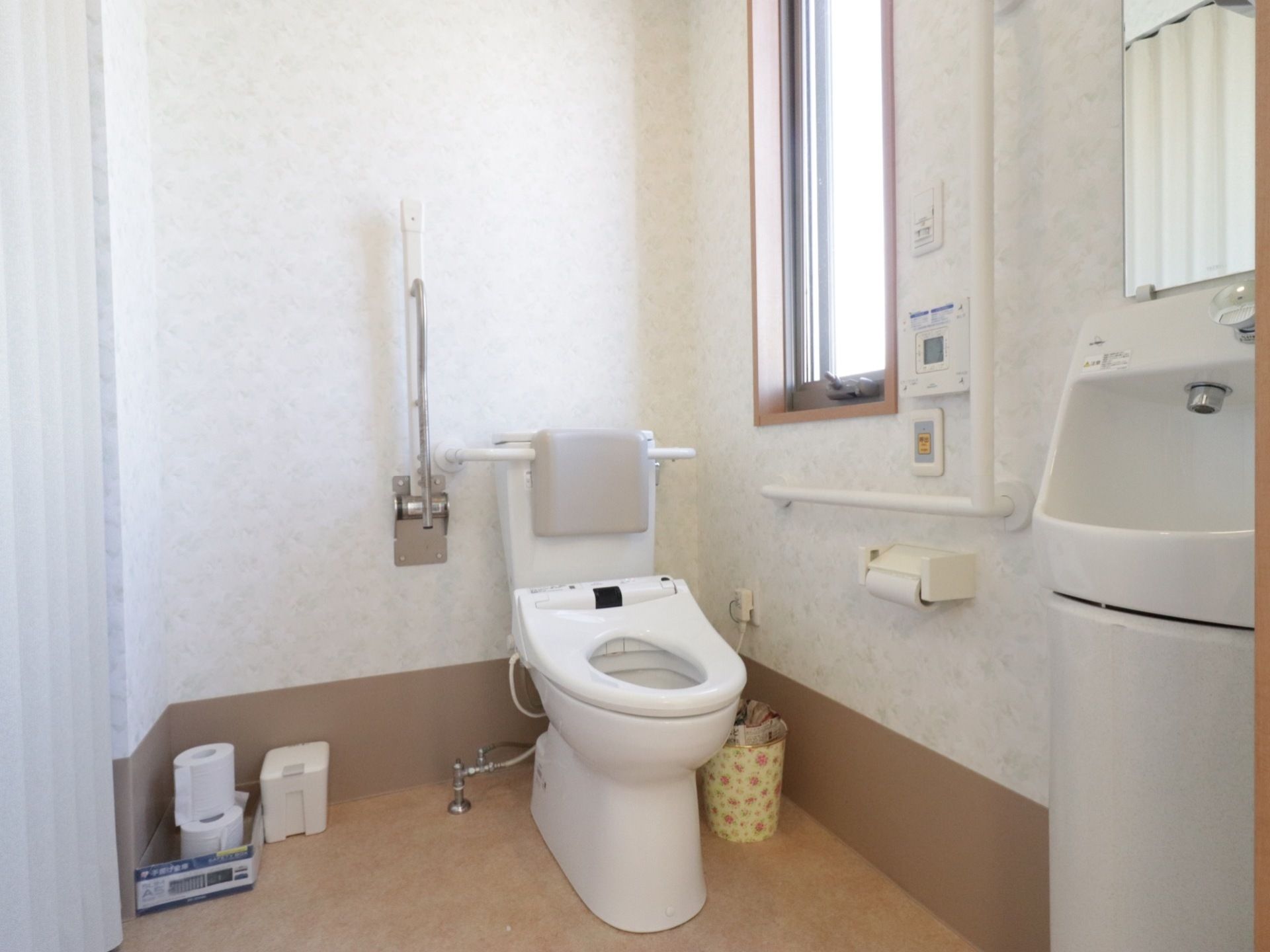 トイレはゆったりとした広さがあり、手すりや背もたれも取りつけられている。室内には、簡易洗面台も設置されている。