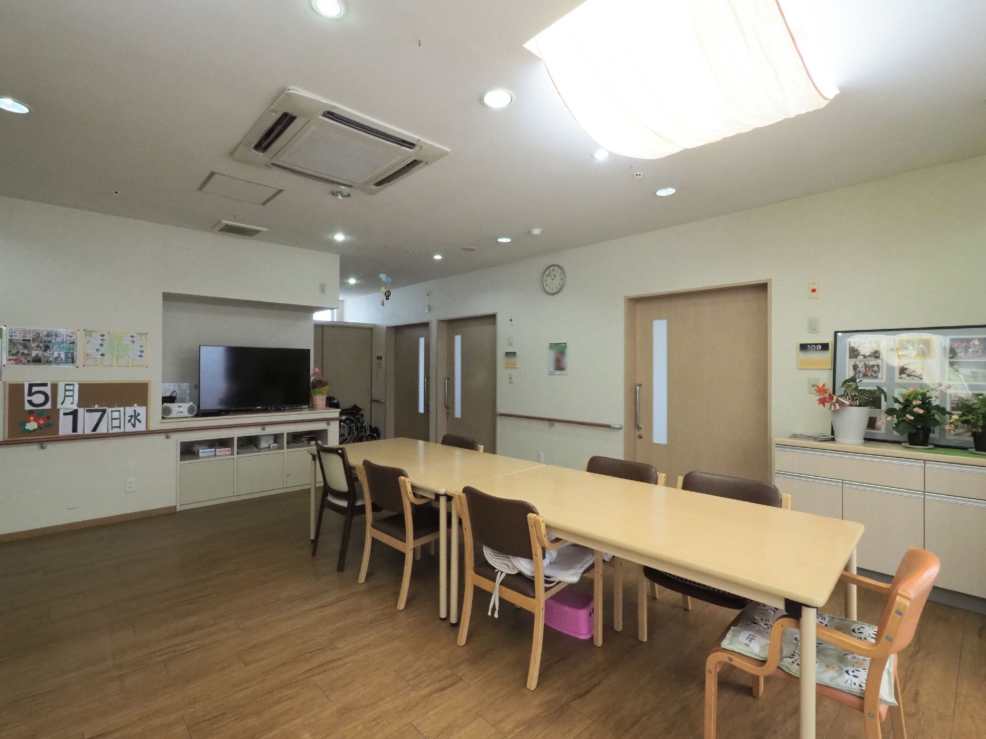 多目的室の奥には居室がある。また、行事が行われた際の記念写真や観葉植物などがカウンターに飾られている。
