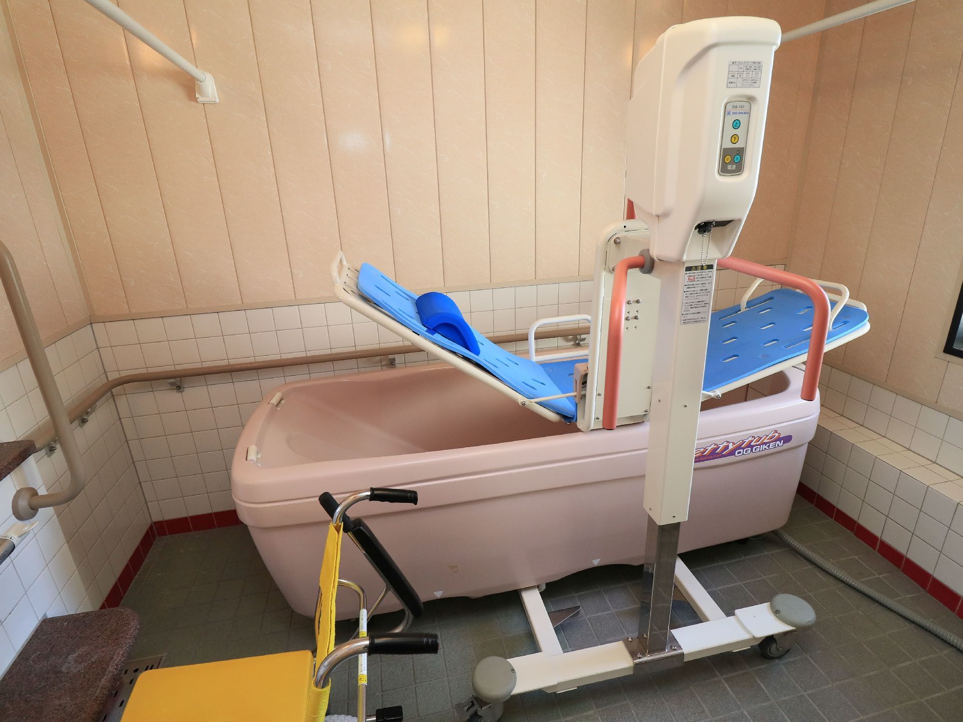 施設内には、リフト機能を用いた入浴システムを完備した浴室がある。白いシートの上に、青いクッション性のあるシートがついている。