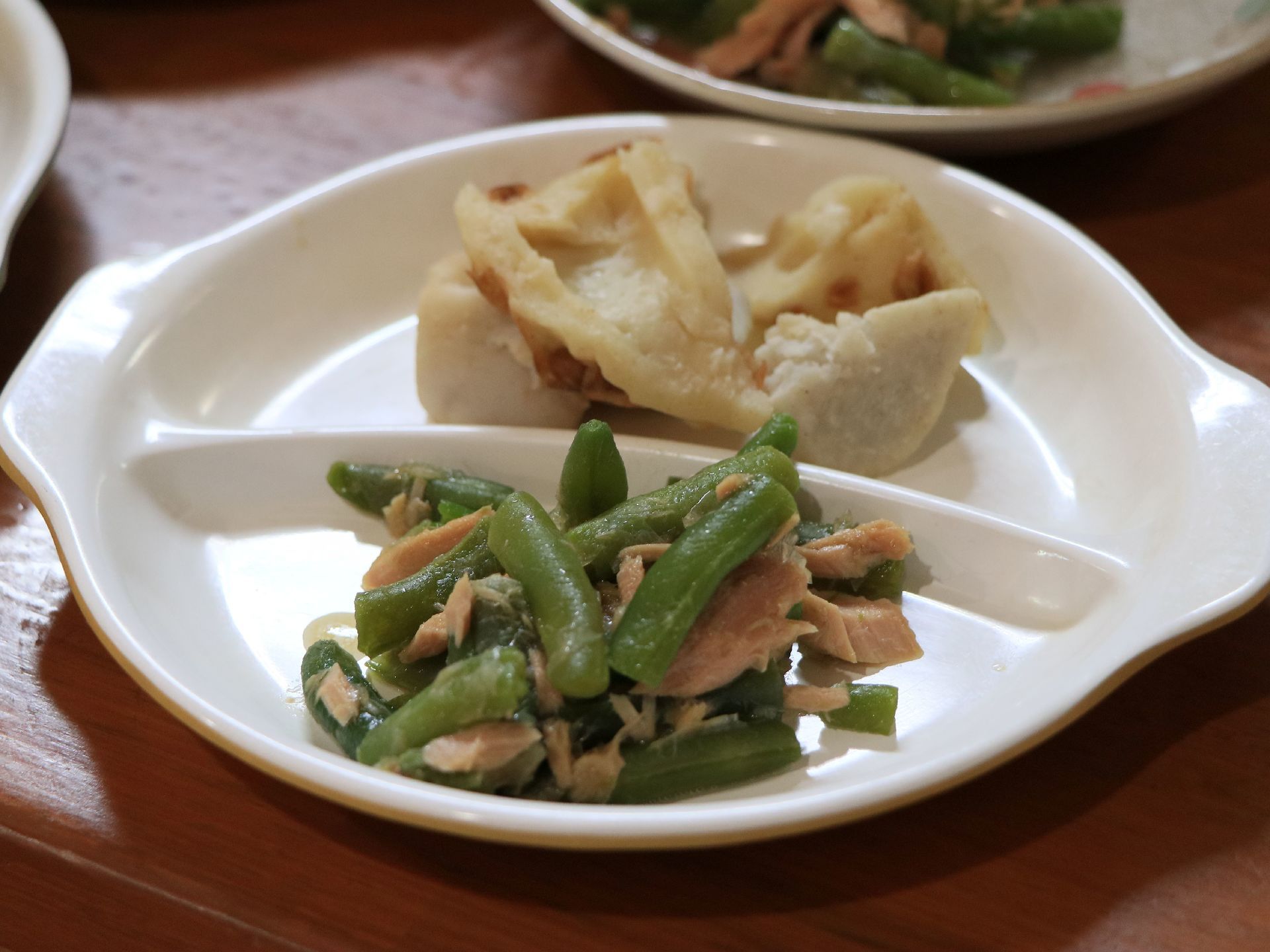 ホームで提供されている食事の例。プラスチック製の白い器は、２つに分かれている。それぞれに、副菜がのっている。