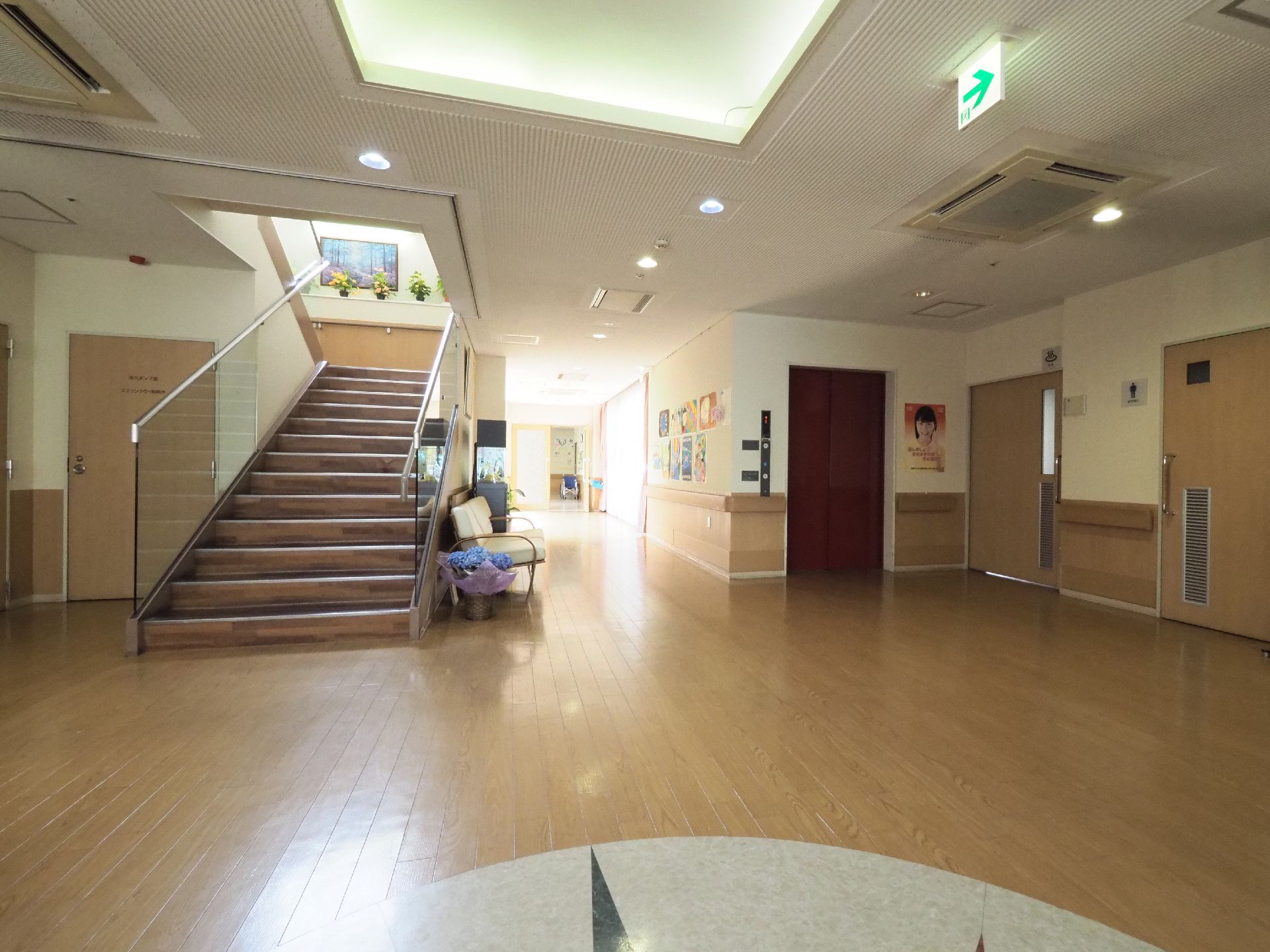 玄関ホールは、天井からも日が差し込む空間。上品なエントランスで、エレベーターや階段があり、随所に花が飾られている。