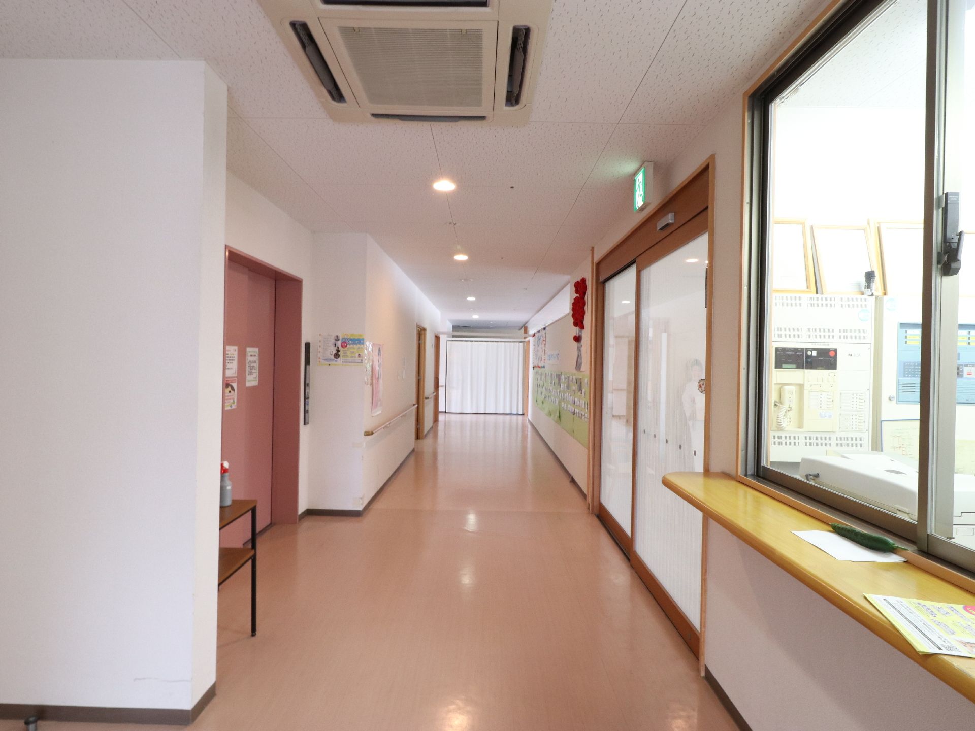 館内に入ると、横に広く廊下がつながっている。入口の目の前にエレベーターがあり、壁には手すりがついている。