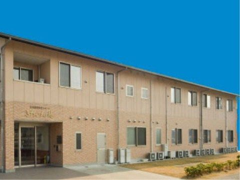 ベージュを基調とした外壁が柔らかい雰囲気の2階建ての建物。玄関まではフラットになっていて楽に出入りができる。