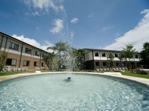 青く晴れた空の下で、噴水の水がきらめいている。噴水の中心から水しぶきが飛び、水面には波紋が広がっている。