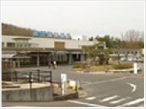 手前に大きなロータリーがあり、その奥に2階建ての横に長い建物が立っている。建物の上には病院名の書かれた青い看板が掲げられている。