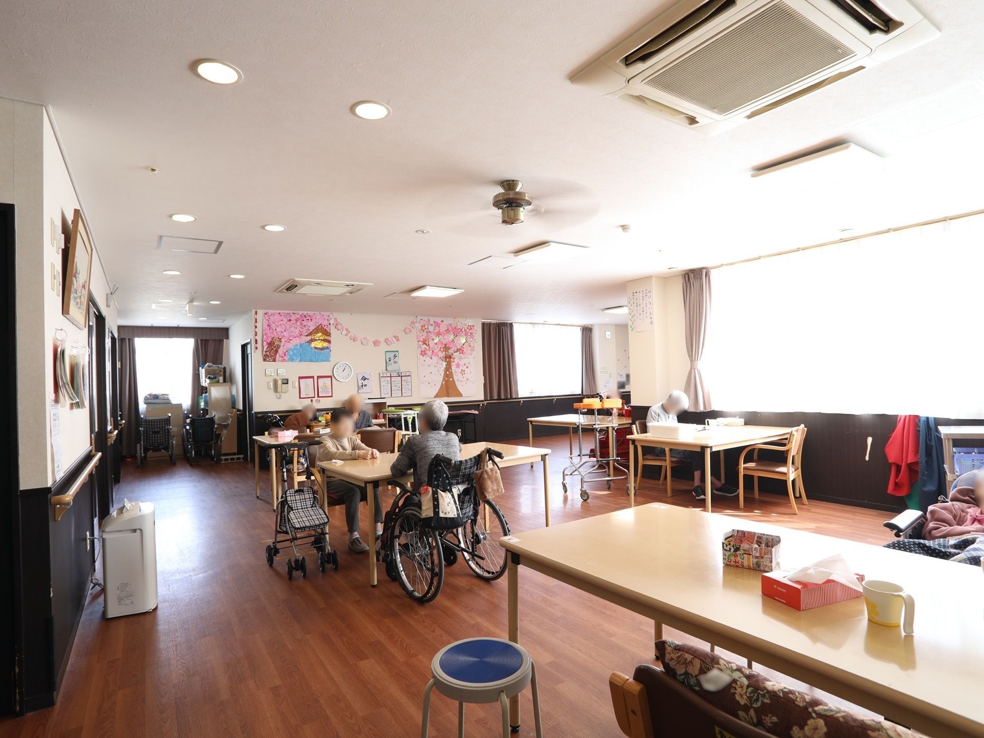 通路に余裕を持ってテーブルが配置されている広い食堂である。壁には季節感あふれる手作りの飾り付けがされている。