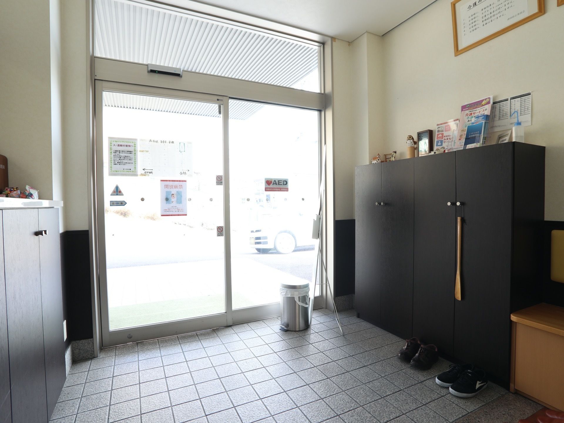 ガラスの自動ドアを入ると風防室になっている。床はタイル貼りで、ここで靴を脱ぐ。入居者様用の靴箱がある。