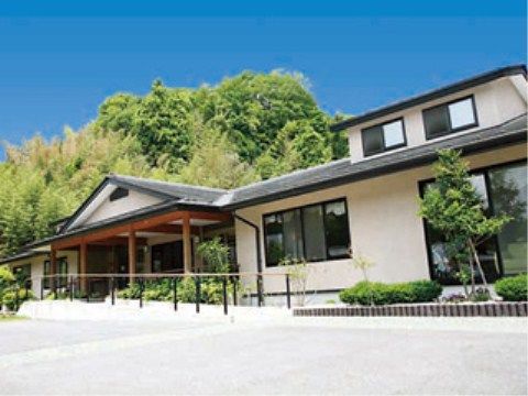 白い壁に黒い瓦屋根が映える和風の建物で、玄関周りは木の柱がひさしを支えている。玄関まではスロープが完備されている。
