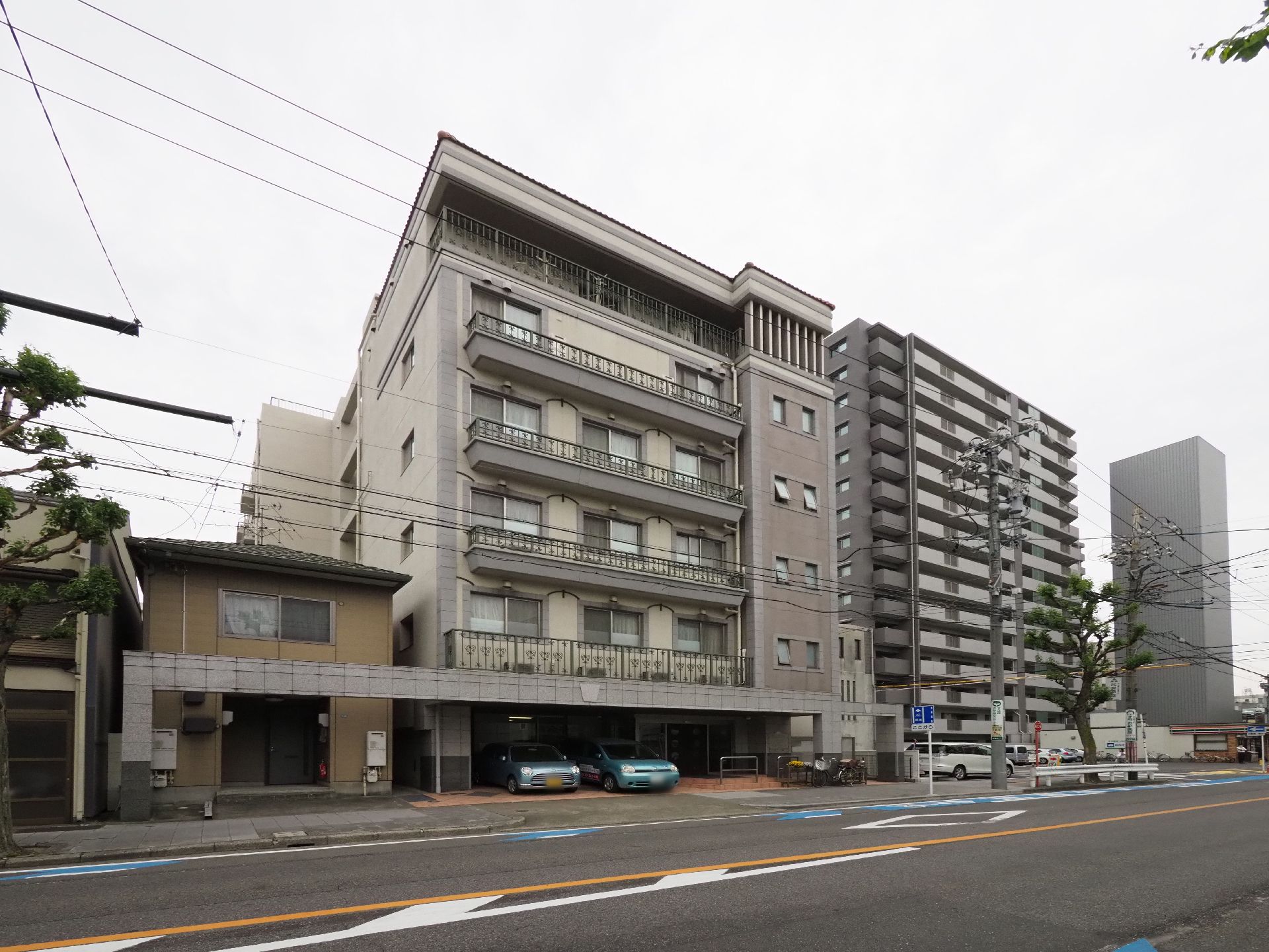 左には住宅右にはマンションがありその間に挟まれている。一階の玄関外のスペースは駐車できるようになっている。