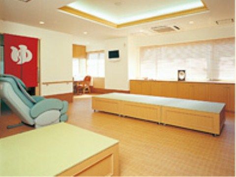 浴室前の休憩所には、マッサージチェアやベンチが並び、銭湯のような雰囲気がある。浴室の入り口には「ゆ」ののれんが下がっている。