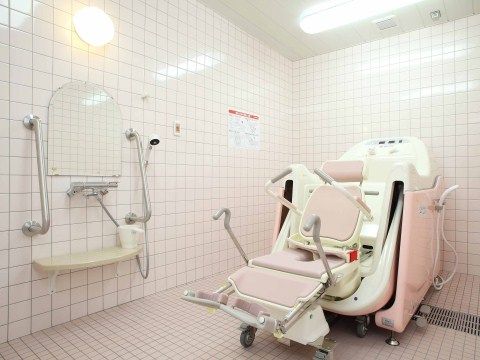 介護度が高い方でも、気持ちよく入浴をお楽しみいただける設備を整えた浴室である。浴槽の前にキャスター付きの椅子を備えている。